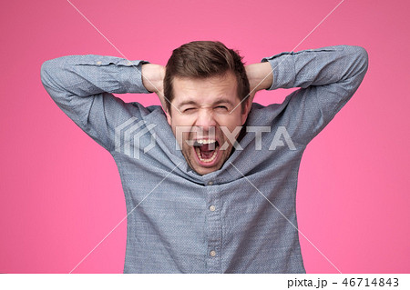 Young man covering his ears and shouting. 46714843