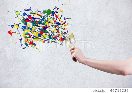 A hand holding paintbrush creating colorful paint splashes A hand holding paintbrush creating colorful paint splashes 46715285