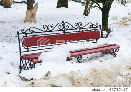 A forged metal bench and wood in the park are thrown in snow during the thaw 46730117