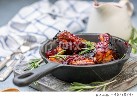 Cast iron pan with baked pork ribs and rosemary. 46730747