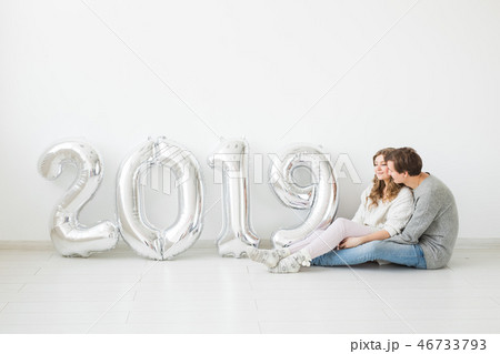 New year, celebration and holidays concept - love couple with sign 2019 made of silver balloons for New year, celebration and holidays concept - love couple with sign 2019 made of silver balloons for 46733793