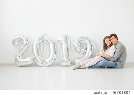 New 2019 Year is coming concept - Happy young man and woman with silver colored numbers on white 46733804