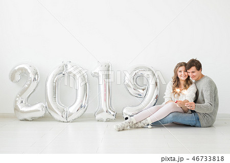 New 2019 Year is coming concept - Happy young man and woman with silver colored numbers on white 46733818