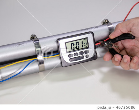 Hand cutting wire on pipe bomb on white background Hand cutting wire on pipe bomb on white background 46735086