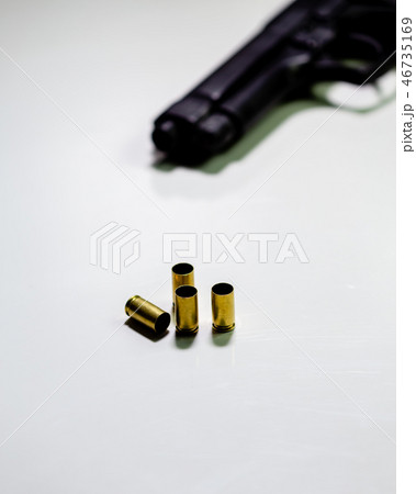 Handgun with 9mm shell casings on white table 46735169