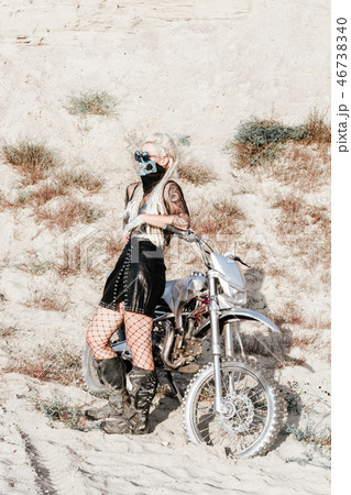 Young blonde woman wearing mask and fishnet tights on motorbike 46738340
