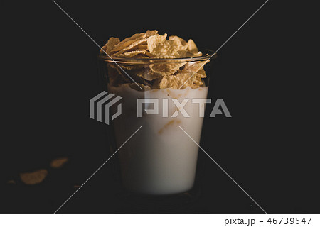 Corn flakes with milk in glass cup isolated on black Corn flakes with milk in glass cup isolated on black 46739547