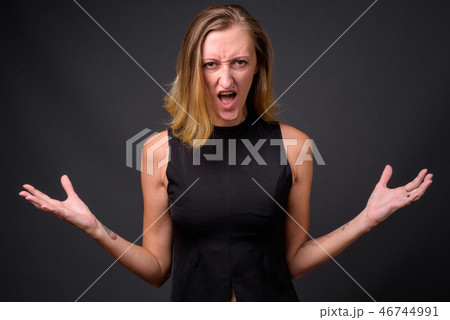 Young beautiful businesswoman with straight blond hair against g Young beautiful businesswoman with straight blond hair against g 46744991