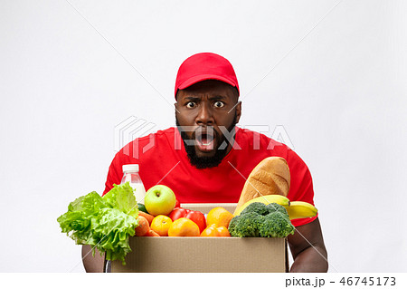 Young african american man holding grocery box in hands with shocking face. Isolated over Grey 46745173