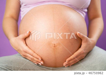 Pregnant woman holding her hands on tummy belly. Young girl expecting baby on pink bakcground Pregnant woman holding her hands on tummy belly. Young girl expecting baby on pink bakcground 46750962