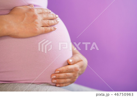 Pregnant woman holding her hands on tummy belly. Young girl expecting baby on pink bakcground Pregnant woman holding her hands on tummy belly. Young girl expecting baby on pink bakcground 46750963