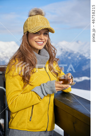 Woman drinking warm tea in the rustick wooden terrace on mountai Woman drinking warm tea in the rustick wooden terrace on mountai 46758215