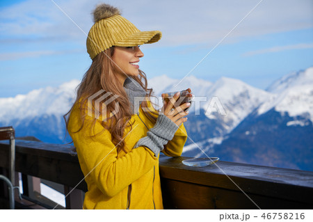 Woman drinking warm tea in the rustick wooden terrace on mountai Woman drinking warm tea in the rustick wooden terrace on mountai 46758216