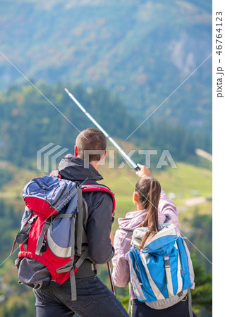 Couple of hikers showing the way with trekking poles up on the mountain peak Couple of hikers showing the way with trekking poles up on the mountain peak 46764123