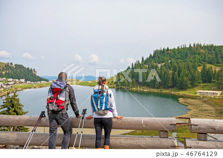 young couple of backpackers near the lake in mountains young couple of backpackers near the lake in mountains 46764129