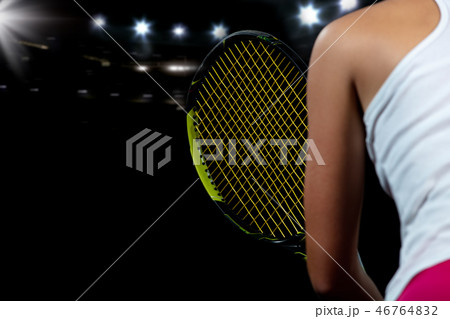 Beautiful girl tennis player with a racket on dark background with lights Beautiful girl tennis player with a racket on dark background with lights 46764832