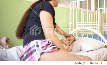 child sleeps in the hospital ward on white bed under the supervision of mom. mother measures child sleeps in the hospital ward on white bed under the supervision of mom. mother measures 46767918
