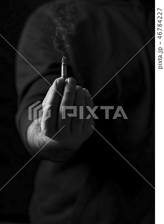 Mans hand holding a smoking cigar in low light 46784227