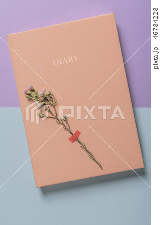 Pink diary notebook and a single white flower. 46784228