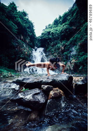 Young woman practice yoga near waterfall in forest Young woman practice yoga near waterfall in forest 46789689