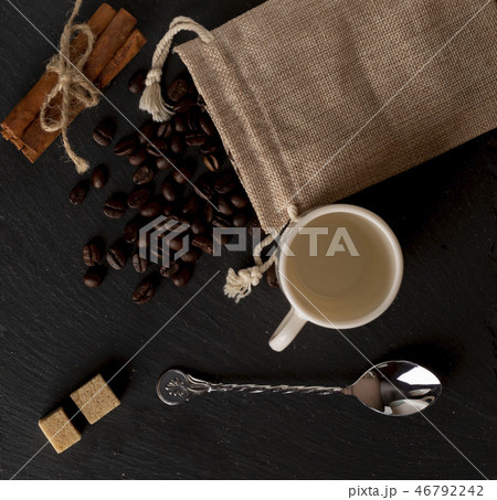 Тоp view burlap with roasted coffee beans, cane sugar, coffee cup on stone surface 46792242