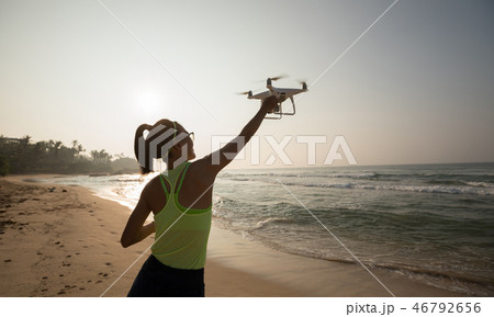 Woman landing or taking off a drone on seaside Woman landing or taking off a drone on seaside 46792656