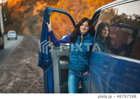brunette woman driver near the car in the autumn forest 46797588