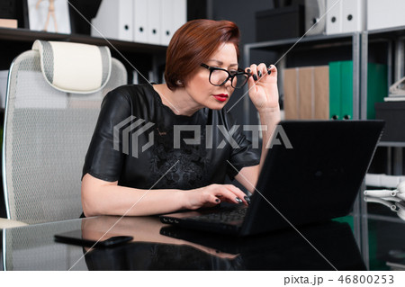 Adult woman holding hand glasses and looking through them in monitor in office Adult woman holding hand glasses and looking through them in monitor in office 46800253