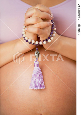 Pregnant woman, lit hand close up, counts Malas, strands of gemstones beads used for keeping count 46800432