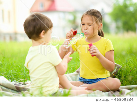 Little girl and boy are blowing soap bubbles Little girl and boy are blowing soap bubbles 46809234