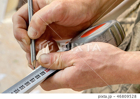 marking piece of pipe with pencil and tape measure 46809528