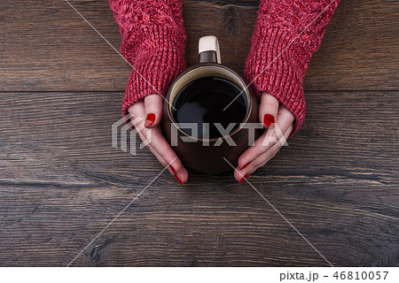 A girl in a red sweater warms her hands 46810057