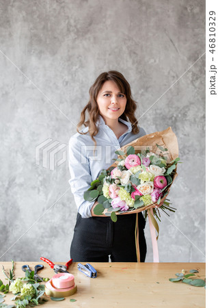 Young friendly smiling female floral artist looking at the camera, holds a luxurious bouquet in his Young friendly smiling female floral artist looking at the camera, holds a luxurious bouquet in his 46810329