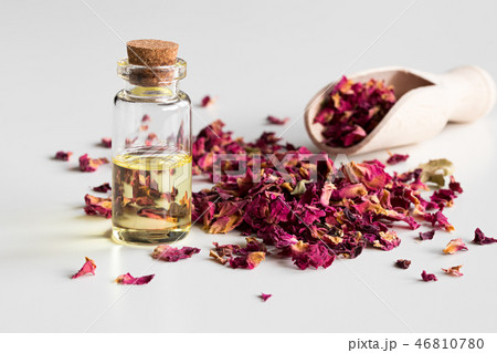 A bottle of rose essential oil with dried petals 46810780