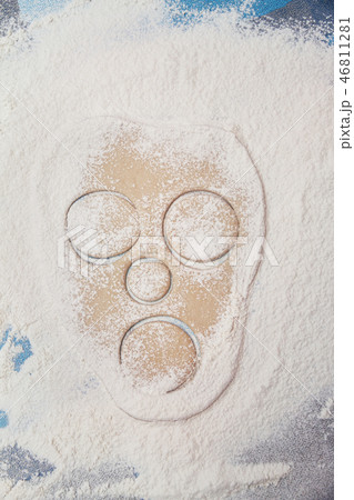raw dough in shape of face rolled out on a flour covered table 46811281