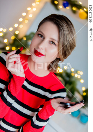 Beautiful woman in red sweater applying lipstick Beautiful woman in red sweater applying lipstick 46812033