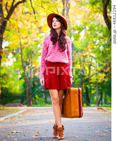 brunet girl with suitcase in the park. 46812294