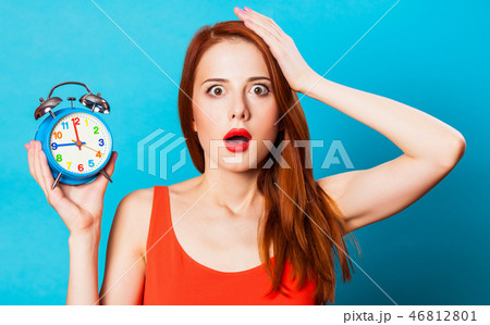 redhead woman woth alarm clock on blue background. 46812801