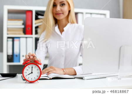 Female hand on the alarm clock a red color stands in 46818867