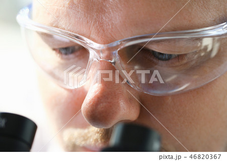 Male scientist looking through binocular Male scientist looking through binocular 46820367