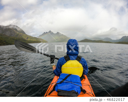 Photo from back of tourist with paddle on canoe floating 46822017
