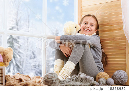 Child girl is sitting on window sill and knitting Child girl is sitting on window sill and knitting 46828982