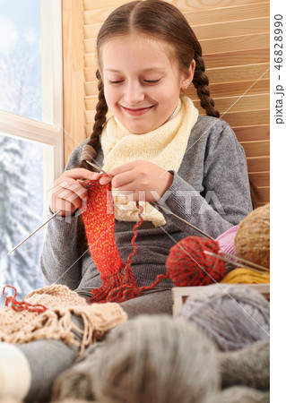 Child girl is sitting on window sill and knitting Child girl is sitting on window sill and knitting 46828990