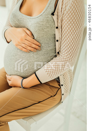 Pregnant woman carefully touching her belly while expecting a baby 46830154