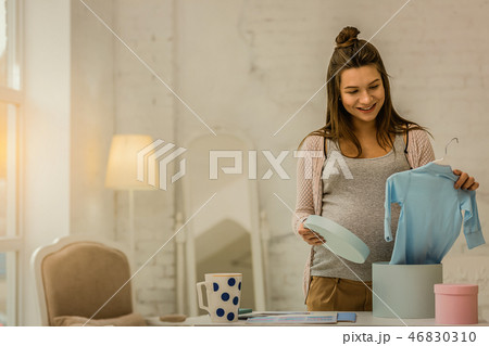 Pregnant woman unpacking the closes for her future baby 46830310