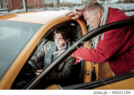 Blonde-haired father assisting his son while choosing car for him Blonde-haired father assisting his son while choosing car for him 46831196