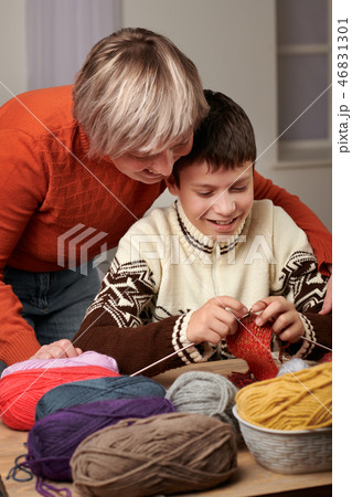 Mother is learning her child boy to knit.  46831301