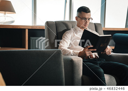 Smart young man wearing glasses reading the Holy Bible Smart young man wearing glasses reading the Holy Bible 46832446