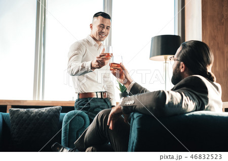 Young man drinking some whisky with his business partner Young man drinking some whisky with his business partner 46832523