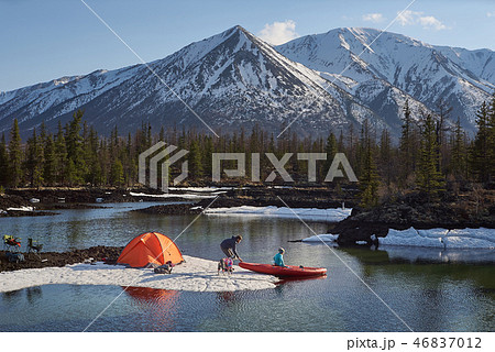 Couple man and woman in a camp at mountain terrain. Lake shore with canoe Couple man and woman in a camp at mountain terrain. Lake shore with canoe 46837012
